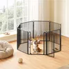 A Corgi dog sits inside a black metal dog playpen in a room with a large window and sheer curtains. Podgląd zdjęcia produktu