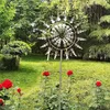 A kinetic wind spinner is displayed in a garden setting with red roses in the foreground. Anteprima dell’immagine prodotto
