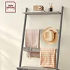 A leaning shelf unit with items displayed on it, against a plain wall. Produktbild-Vorschau