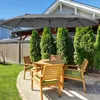 An outdoor patio set with a large umbrella, table, and chairs on a gravel and grass area. Podgląd zdjęcia produktu