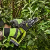 A person wearing gloves is using a cordless electric chainsaw to prune branches from a tree. Produktbild-Vorschau