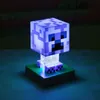 A Minecraft Creeper lamp with blue and white pixelated patterns, standing on a green grass block base. Náhled obrázku produktu