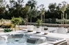 A hot tub with potted plants on the edge, set in an outdoor garden. Anteprima dell’immagine prodotto