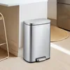 A stainless steel trash can with a foot pedal is placed next to a kitchen counter. Podgląd zdjęcia produktu