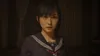A young woman in a school uniform looks directly at the camera in a dimly lit room. Produktbild-Vorschau