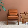 A stylish armchair in a warm terracotta color is placed in a room with a terracotta-colored wall and a patterned rug. Produktbild-Vorschau