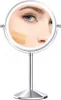 A close-up reflection of a woman's face in a makeup mirror, showing foundation swatches on her cheek. Produktbild-Vorschau
