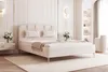 A modern, cream-colored bed with golden legs and decorative pillows, set in a well-lit bedroom with elegant wall paneling and decorative sconces. Náhled obrázku produktu