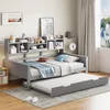 A daybed with a trundle bed pulled out, set up in a bedroom with shelves above the headboard displaying decorative items and books. Náhled obrázku produktu