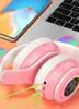 A close-up shot of pink and white wireless headphones with LED lights, placed next to a smartphone and a laptop. Produktbild-Vorschau