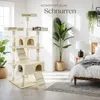 A cat tree is shown in a bedroom setting next to a bed and plants. Voir les images du produit