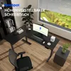 An L-shaped standing desk in a modern office setting with a large window overlooking a green landscape. Náhled obrázku produktu