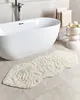 A modern bathroom with a freestanding bathtub and a beige bath mat. Náhled obrázku produktu