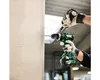 A person wearing gloves is using a cordless drill to drill into a concrete column. Produktbild-Vorschau