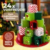 A Christmas advent calendar made of wooden cubes, stacked in a pyramid shape, with a Christmas tree in the background. Produktbild-Vorschau