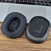 Two ear pads for headphones are placed on a wooden surface in front of a laptop. Náhled obrázku produktu