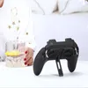 A gaming controller with cooling fans is placed on a white surface next to a glass of water with lemon. A person's arm and shoulder are visible on the left side of the image. Náhled obrázku produktu