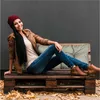 A woman is sitting on a pallet bench with a cushion, surrounded by fallen leaves. Náhled obrázku produktu
