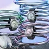 Three Casio G-Shock watches in different colors are displayed on a reflective surface, surrounded by metallic rings. Produktbild-Vorschau