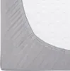 A close-up view of a grey fitted sheet with elastic edging, partially covering a white mattress with a wavy pattern. Náhled obrázku produktu