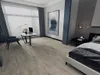 A modern bedroom and home office setup with a bed, nightstand, desk, and chair. Produktbild-Vorschau