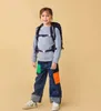 A young girl wearing a backpack and jeans stands against a plain background. Anteprima dell’immagine prodotto