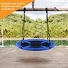 A blue nest swing is hanging from a wooden beam over a wooden deck, with a body of water and trees in the background. Voir les images du produit