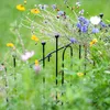 A close-up view of a black metal garden fence border with various wildflowers growing around and through it. Podgląd zdjęcia produktu