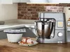 A kitchen scene featuring a stand mixer and an ice cream maker attachment, with a serving of ice cream in the foreground. Anteprima dell’immagine prodotto