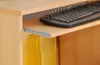 A close-up view of a keyboard on a pull-out shelf of a wooden desk, with yellow file holders underneath. Produktbild-Vorschau
