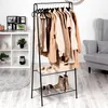 A black metal garment rack with clothes and shoes on shelves, next to a white shelving unit and a gray armchair. Produktbild-Vorschau