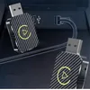 Two USB adapters with a carbon fiber pattern and a yellow play button logo are shown plugged into a car's USB port. Produktbild-Vorschau