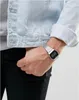 A close-up shot of a person's wrist wearing a silver digital watch, with a denim jacket visible. Produktbild-Vorschau