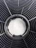 Close-up of a black circular fan grill with a central opening. Anteprima dell’immagine prodotto