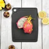 A black cutting board with a dragon fruit cut in half and two lemon slices on a white wooden background. Anteprima dell’immagine prodotto
