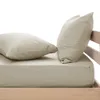 A close-up view of a beige fitted sheet and two pillows on a wooden bed frame. Produktbild-Vorschau