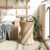 A balcony setting with a wicker side table holding a mug and a plate, next to a sofa with cushions and a blanket. Produktbild-Vorschau