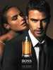 A man in a suit is shown with a woman whispering in his ear, with a bottle of Hugo Boss The Scent perfume in the foreground. Náhľad obrázku produktu