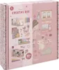 A pink cardboard box for a creative craft kit, decorated with floral patterns and illustrations of a girl, a bunny, and various craft supplies. Produktbild-Vorschau