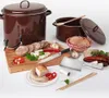 A collection of food preparation items, including pots, sausages, bread, and utensils, arranged on a white surface. Podgląd zdjęcia produktu