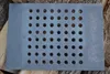 A gray cast iron grate with many circular holes is placed on top of a pile of logs. Produktbild-Vorschau