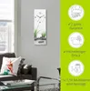 A wall clock with a zen-like image of stones and grass is displayed on a wall above a sofa. To the right, there are marketing graphics highlighting product features. Produktbild-Vorschau