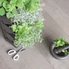A vertical planter with various herbs and plants, along with scissors and a mortar and pestle, arranged on a wooden floor. Náhled obrázku produktu