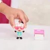 A child's hand holds a small toy cat figure wearing sunglasses and a blue shirt. Next to it is a pink and white toy accessory. Anteprima dell’immagine prodotto