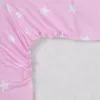 A close-up view of a pink crib sheet with white stars, showing the elasticized edge. Produktbild-Vorschau