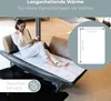 A woman is relaxing on a couch while reading a book, with a heating pad laid out on the couch. Produktbild-Vorschau