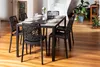 A dining table set with chairs in a well-lit room with wooden floors and plants. Anteprima dell’immagine prodotto