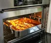 A roasting pan filled with food is placed inside an oven. Produktbild-Vorschau