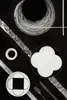 A flat lay arrangement of black and white plates and cutlery on a black background with silver accents. Produktbild-Vorschau