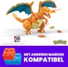 A Pokemon Charizard building block toy with accompanying Pokemon balls and text overlays indicating compatibility with other brands. Voir les images du produit